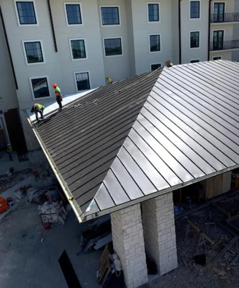 Crew installing standing seam metal roof panels on a commercial project in Fort Wright